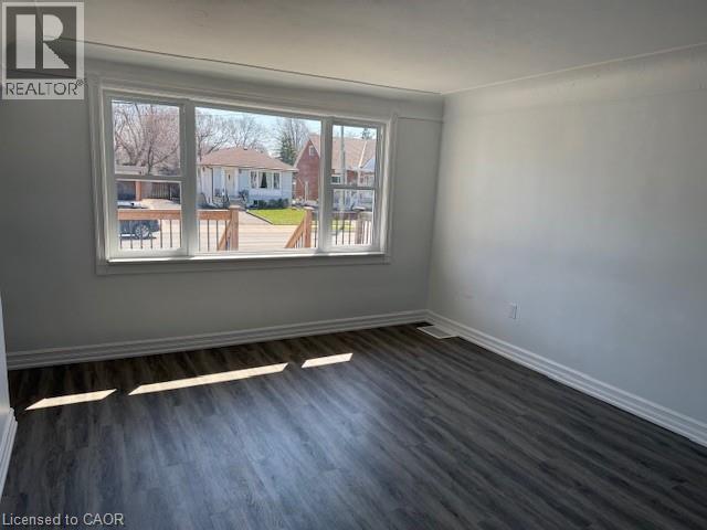 Spare room with dark wood finished floors and a residential view - 322 Upper Gage Avenue, Hamilton, ON - Indoor Photo Showing Other Room