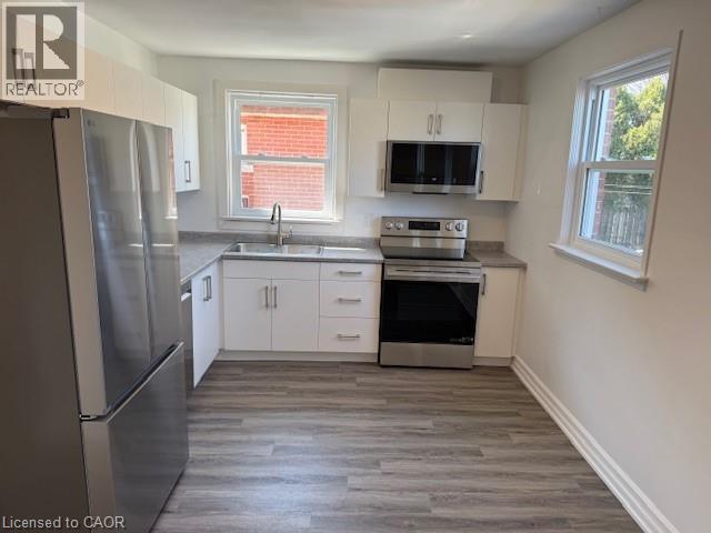 Kitchen featuring stainless steel appliances, white cabinets, and light wood-style floors - 322 Upper Gage Avenue, Hamilton, ON - Indoor Photo Showing Kitchen