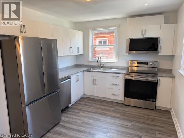 Kitchen with stainless steel appliances, white cabinets, dark wood-style flooring, and light countertops - 322 Upper Gage Avenue, Hamilton, ON - Indoor Photo Showing Kitchen
