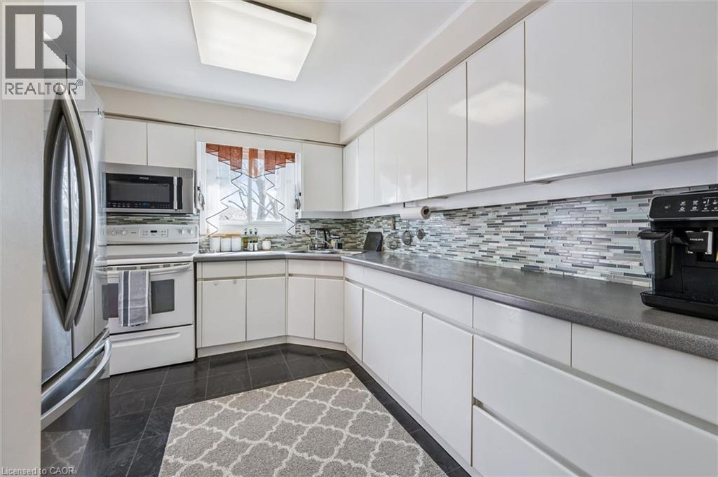 Kitchen with stainless steel appliances, white cabinets, backsplash, and dark countertops - 55 Ralgreen Crescent, Kitchener, ON - Indoor Photo Showing Kitchen