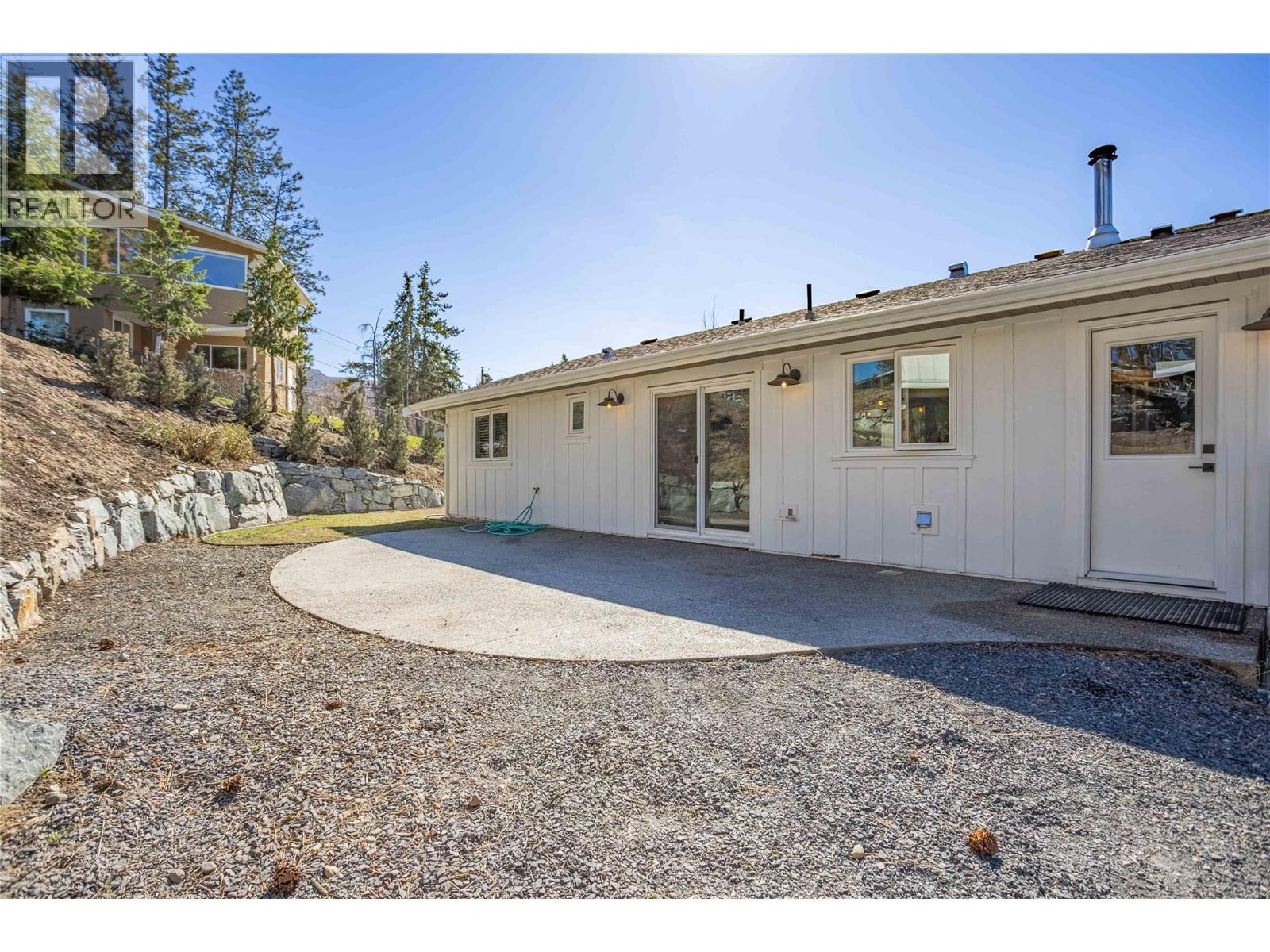 Back of house with flat grass area and aggregate patio - 488 Sheila Crescent, Kelowna, BC - Outdoor