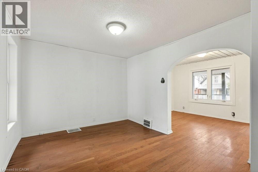 Spare room featuring hardwood / wood-style flooring, arched walkways, and a textured ceiling - 23 Frederick Avenue, Hamilton, ON - Indoor Photo Showing Other Room