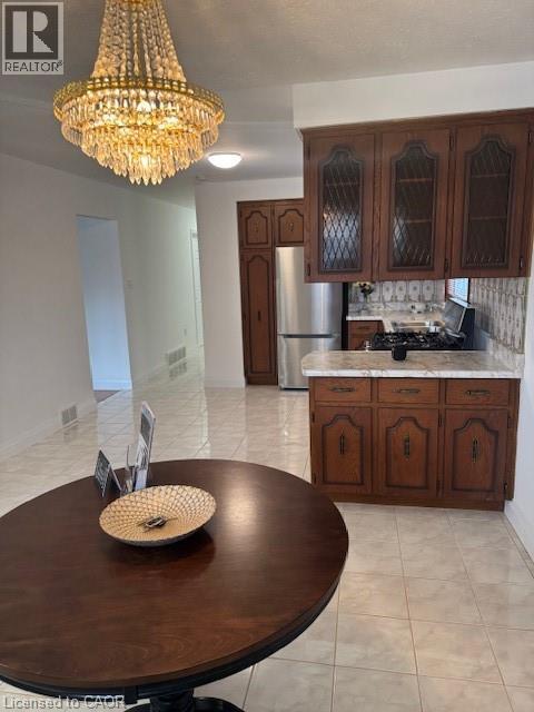 Kitchen featuring glass fronted cabinets, stainless steel appliances, hanging lights, and light tile patterned floors - 31 Adair Avenue, Hamilton, ON - Indoor Photo Showing Kitchen