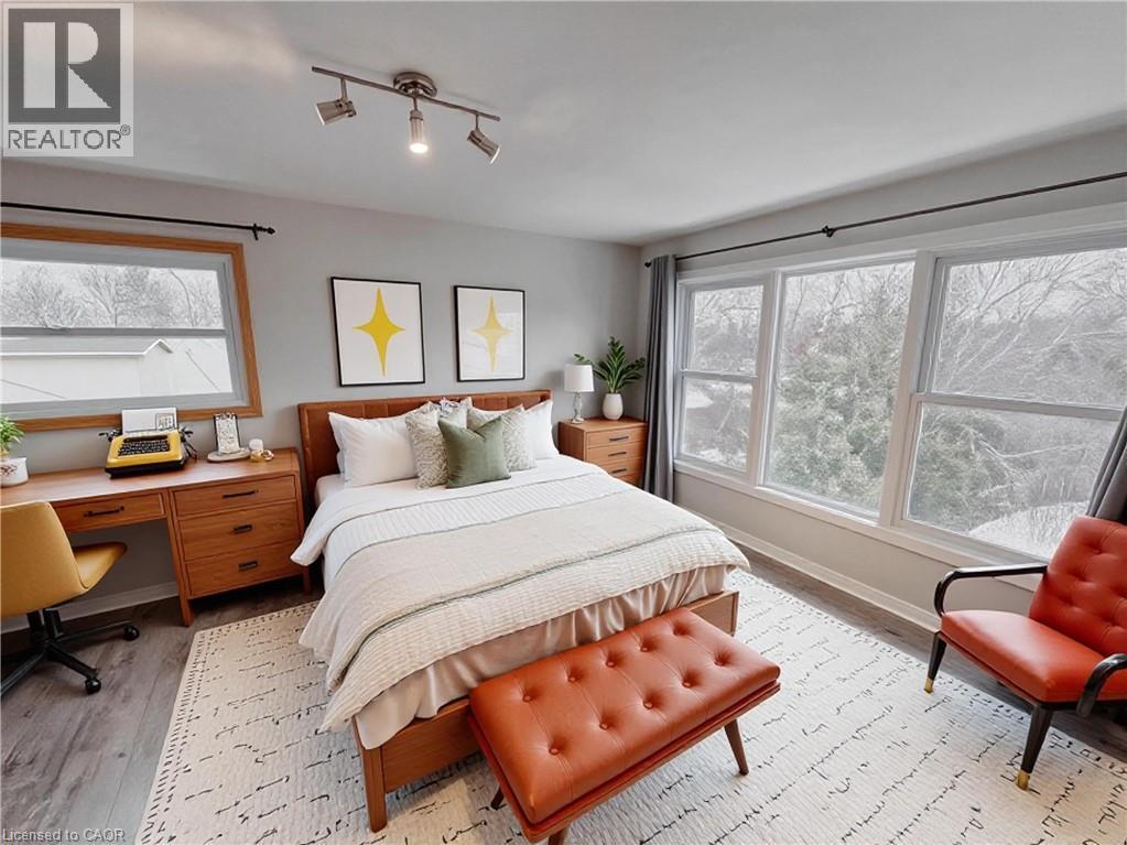 Bedroom with a desk, light wood-style flooring, and multiple windows. 2nd level. Virtually staged. - 122 Weber Street S, Waterloo, ON - Indoor Photo Showing Bedroom