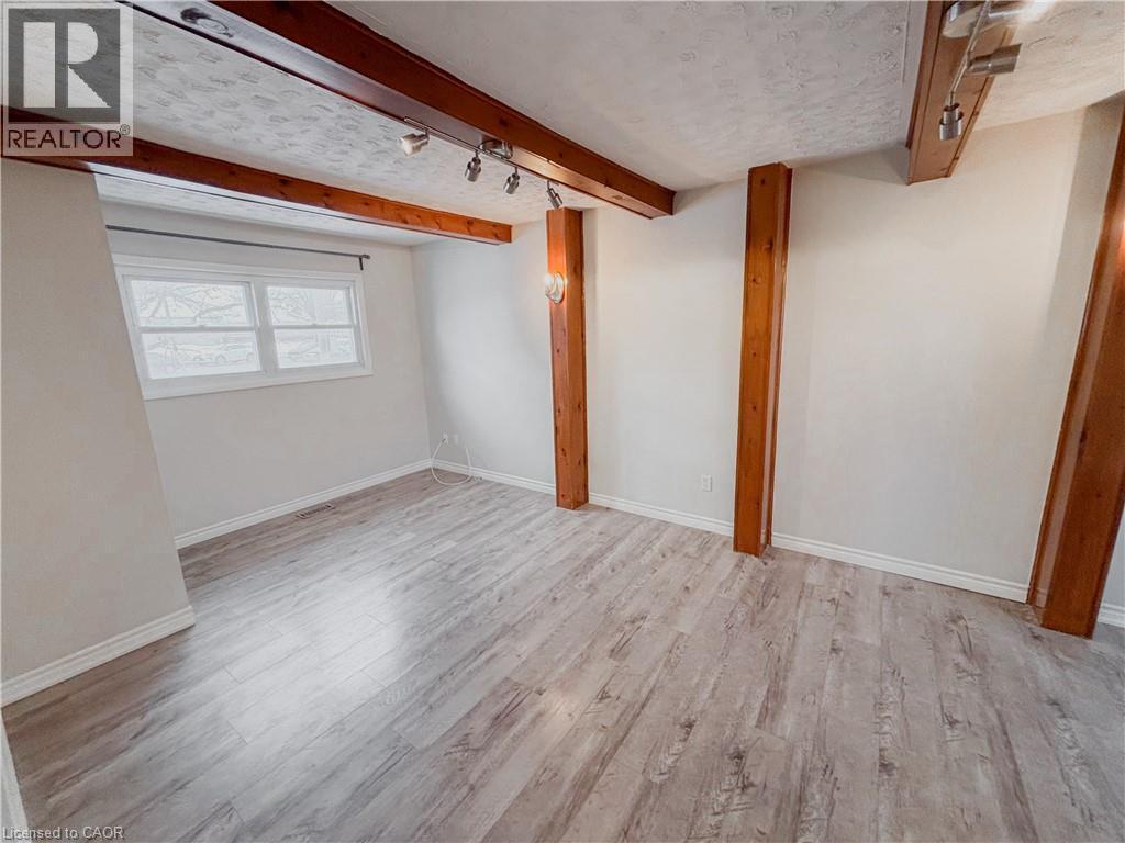 Empty room featuring beamed ceiling, light wood-style flooring, and a textured ceiling - 122 Weber Street S, Waterloo, ON - Indoor Photo Showing Other Room