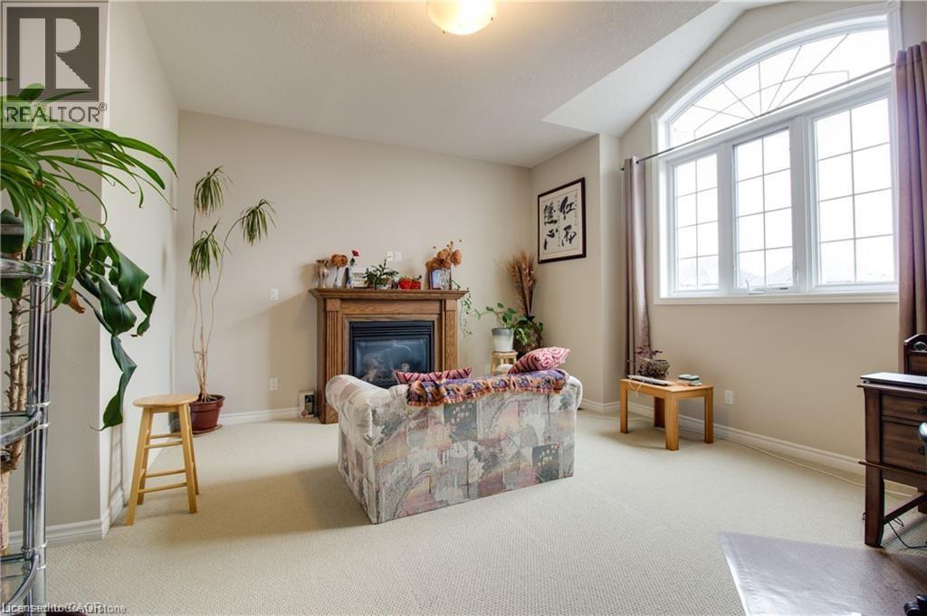 Sitting room with light colored carpet and lofted ceiling - 101 Robert Simone Way, Ayr, ON - Indoor With Fireplace