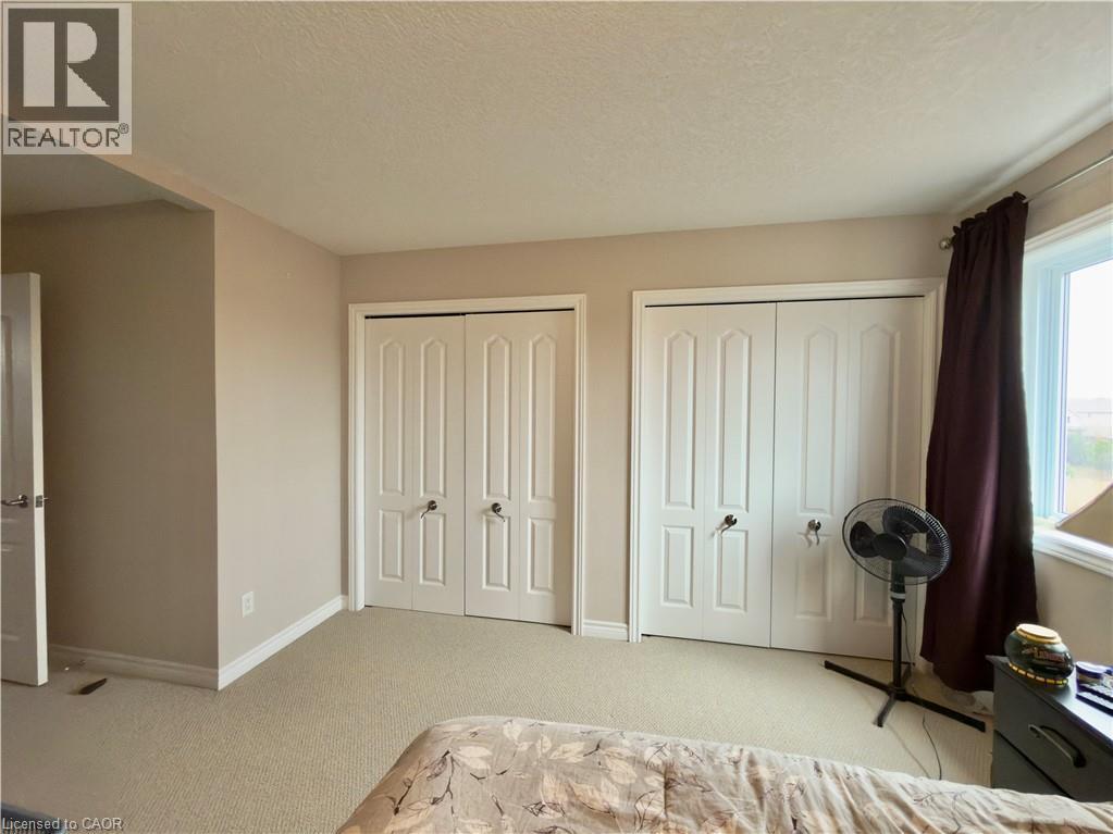 Bedroom with multiple closets, light carpet, and a textured ceiling - 101 Robert Simone Way, Ayr, ON - Indoor Photo Showing Bedroom