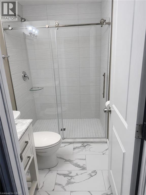 This bathroom features a contemporary shower with a glass sliding door and light-colored tiled walls - 61 Bosworth Crescent Unit# Upper, Kitchener, ON - Indoor Photo Showing Bathroom