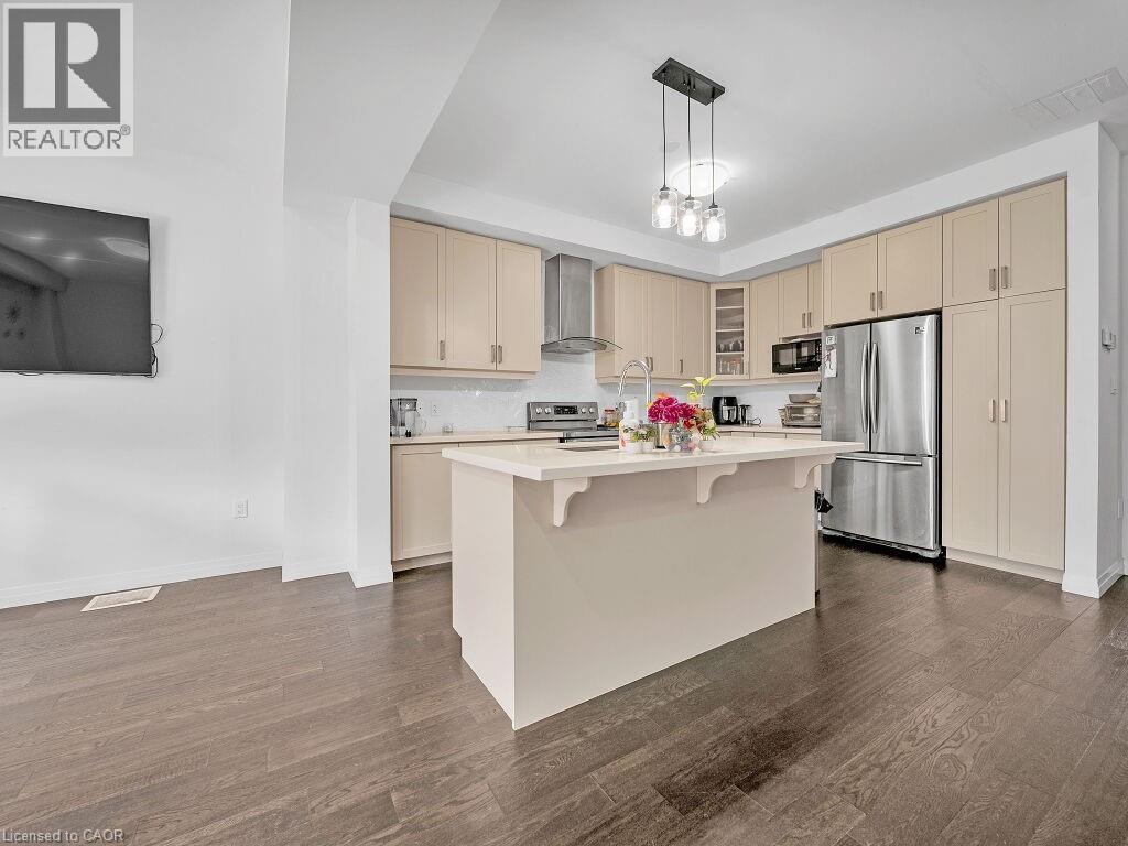 Kitchen featuring stainless steel appliances, cream cabinetry, a center island with sink, a breakfast bar area, and glass fronted cabinets - 30 Times Square Boulevard, Hamilton, ON - Indoor Photo Showing Kitchen