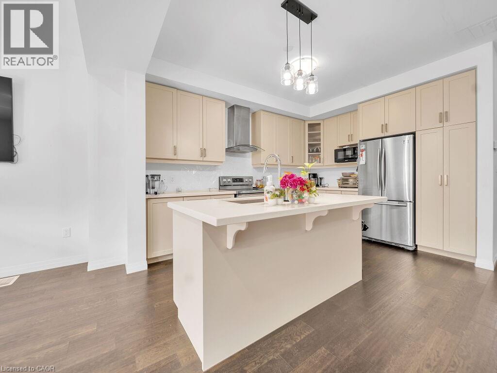 Kitchen with cream cabinets, stainless steel appliances, a center island with sink, and dark wood-style floors - 30 Times Square Boulevard, Hamilton, ON - Indoor Photo Showing Kitchen