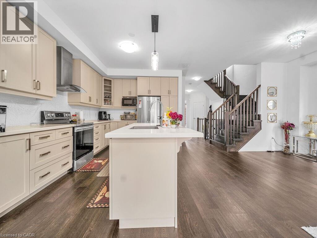 Kitchen with cream cabinets, stainless steel appliances, glass insert cabinets, an island with sink, and dark wood-style floors - 30 Times Square Boulevard, Hamilton, ON - Indoor Photo Showing Kitchen With Upgraded Kitchen