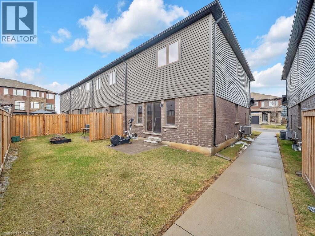 Rear view of property with brick siding, entry steps, an outdoor fire pit, and a fenced backyard - 30 Times Square Boulevard, Hamilton, ON - Outdoor