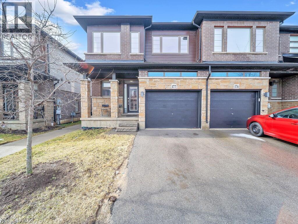 Modern home with an attached garage, driveway, stone siding, and brick siding - 30 Times Square Boulevard, Hamilton, ON - Outdoor With Facade