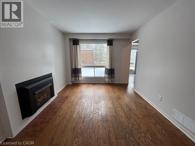 Unfurnished living room featuring dark wood-type flooring and a glass covered fireplace - 536 Thorndale Drive, Waterloo, ON - Indoor With Fireplace