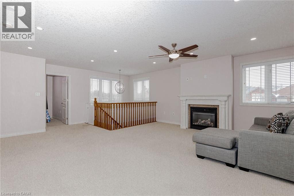 Living area with light carpet, ceiling fan, a textured ceiling, a glass covered fireplace, and recessed lighting - 2 Doon Creek Street, Kitchener, ON - Indoor Photo Showing Living Room With Fireplace
