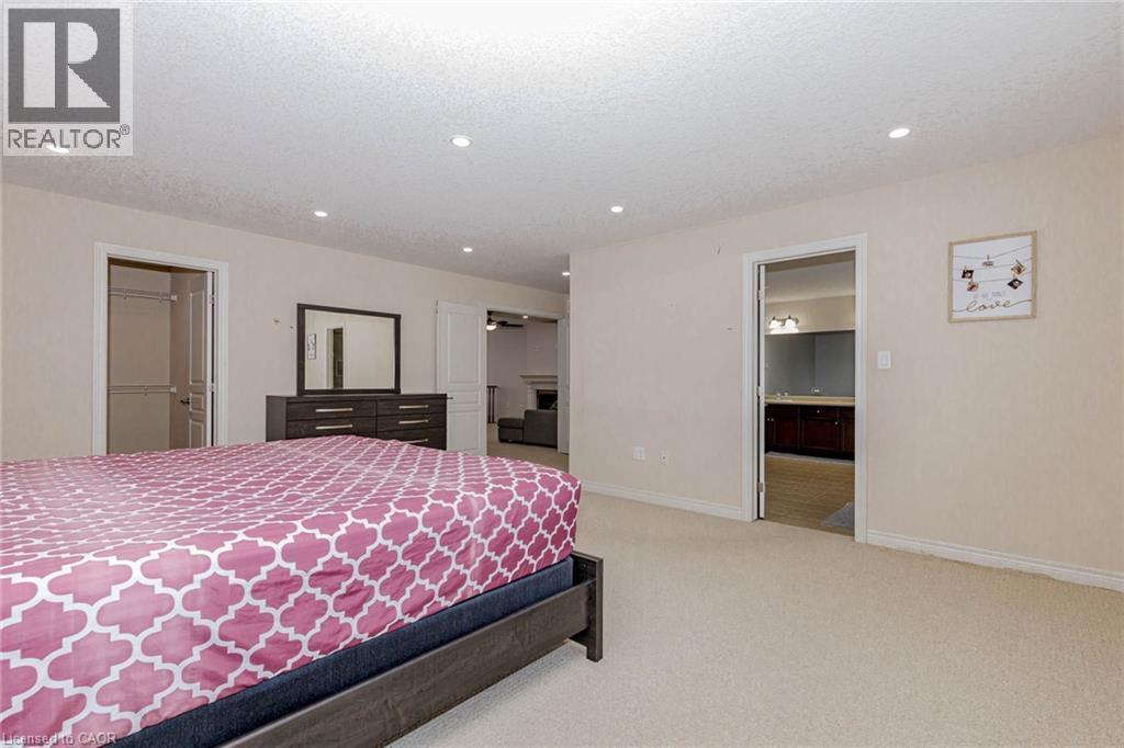 Bedroom with light colored carpet, a walk in closet, recessed lighting, and a textured ceiling - 2 Doon Creek Street, Kitchener, ON - Indoor Photo Showing Bedroom