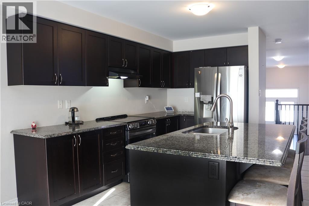 Kitchen featuring stainless steel refrigerator with ice dispenser, dark stone countertops, dark cabinets, electric range, and a kitchen island with sink - 31 Sofitel Drive, Kitchener, ON - Indoor Photo Showing Kitchen With Upgraded Kitchen