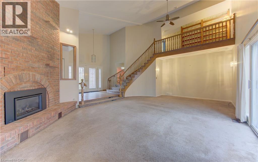 Unfurnished living room featuring a high ceiling, carpet flooring, a ceiling fan, a fireplace, and french doors - 190 Silvercrest Drive, Waterloo, ON - Indoor With Fireplace