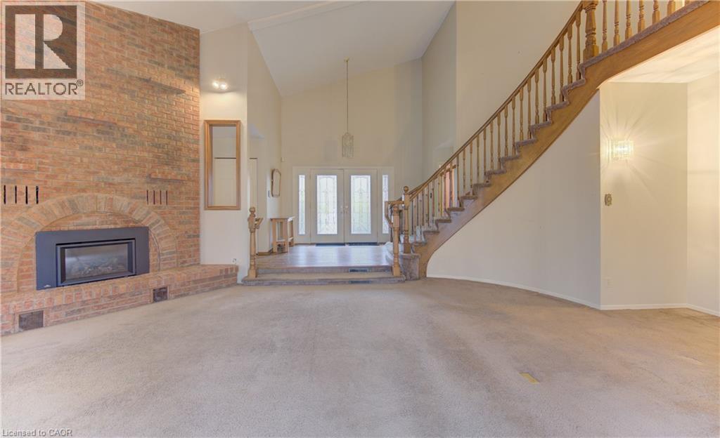 Unfurnished living room featuring vaulted ceiling, carpet, a brick fireplace, and french doors - 190 Silvercrest Drive, Waterloo, ON - Indoor With Fireplace