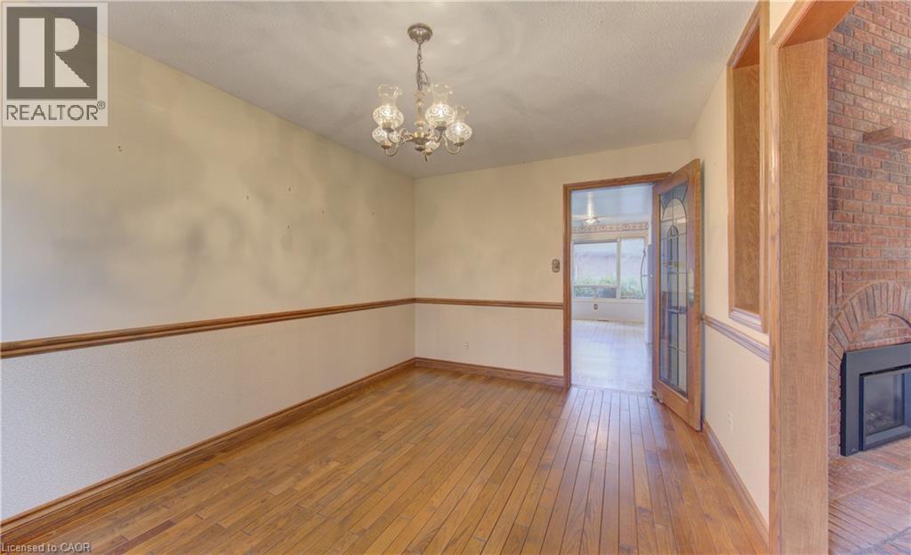 Empty room featuring a brick fireplace, a chandelier, and wood-type flooring - 190 Silvercrest Drive, Waterloo, ON - Indoor Photo Showing Other Room