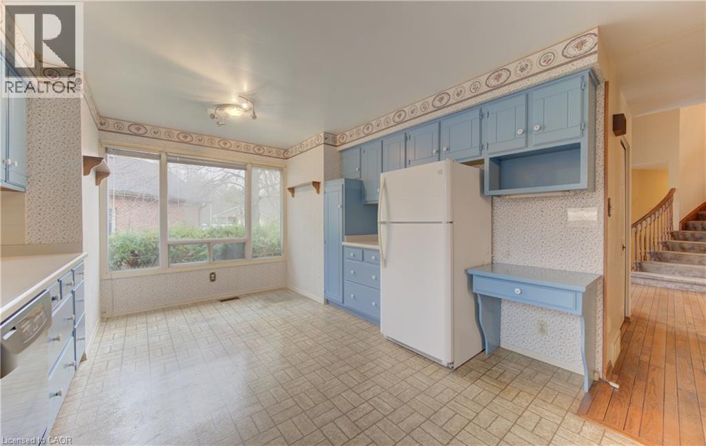 Kitchen featuring blue cabinetry, wallpapered walls, brick patterned floors, freestanding refrigerator, and dishwashing machine - 190 Silvercrest Drive, Waterloo, ON - Indoor