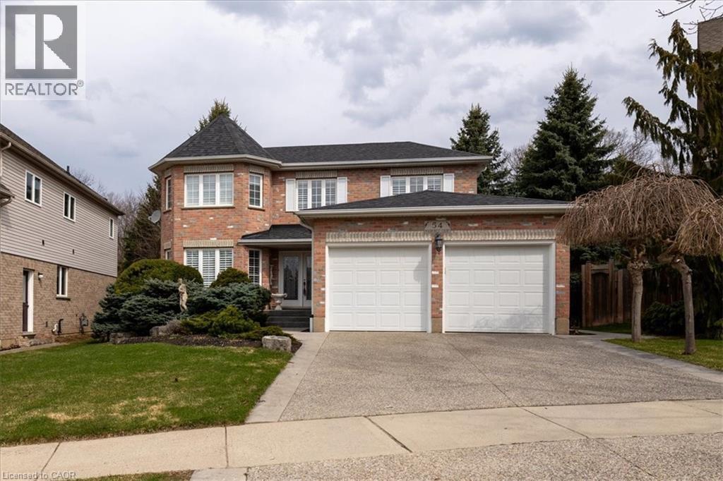 Traditional-style house featuring brick siding, a garage, a front lawn, and driveway - 54 Woodcrest Court, Kitchener, ON - Outdoor With Facade