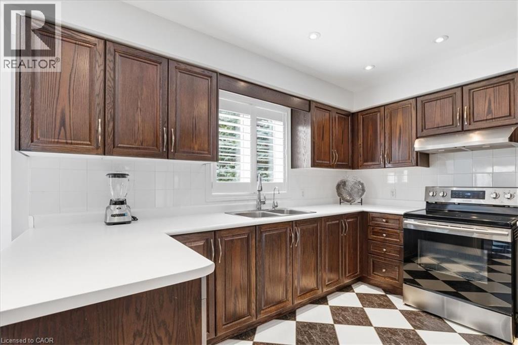 Kitchen with stainless steel range with electric cooktop, light flooring, light countertops, dark wood finish cabinets, and tasteful backsplash - 54 Woodcrest Court, Kitchener, ON - Indoor Photo Showing Kitchen With Double Sink