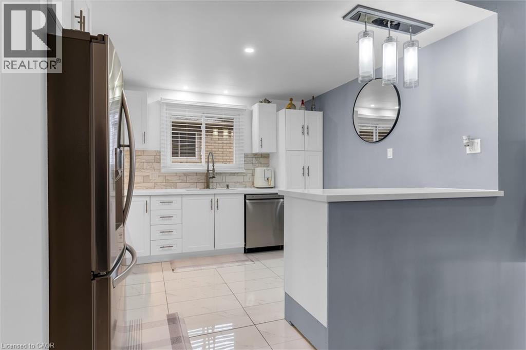 Kitchen featuring white cabinetry, stainless steel appliances, decorative backsplash, and pendant lighting - 51 Independence Drive, Hamilton, ON - Indoor Photo Showing Kitchen