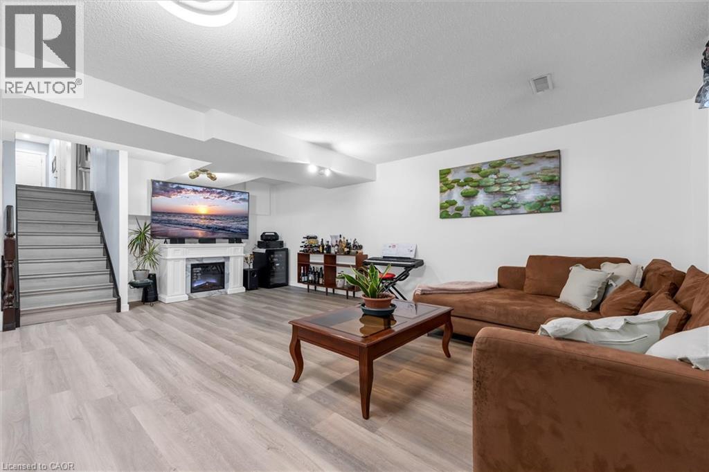 Living area with light wood-type flooring, a glass covered fireplace, and a textured ceiling - 51 Independence Drive, Hamilton, ON - Indoor Photo Showing Living Room With Fireplace