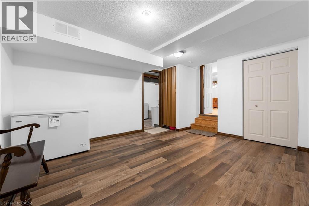 Finished basement with a textured ceiling, dark wood-style floors, and fridge - 51 Independence Drive, Hamilton, ON - Indoor Photo Showing Other Room