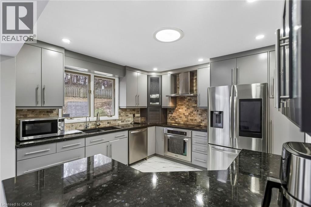 Kitchen with gray cabinetry, stainless steel appliances, dark stone counters, glass insert cabinets, and backsplash - 3 Chicopee Terrace, Kitchener, ON - Indoor Photo Showing Kitchen With Double Sink With Upgraded Kitchen