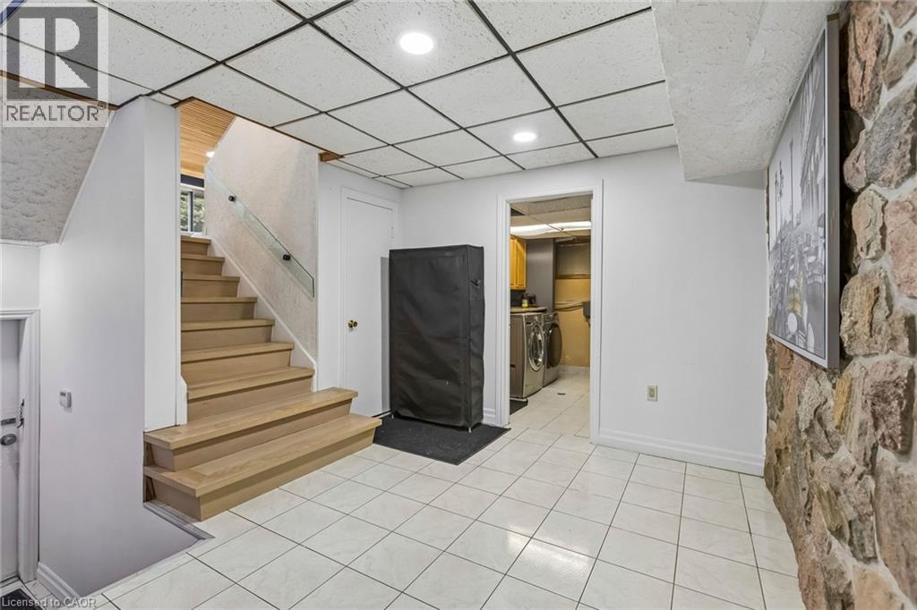 Finished basement featuring light tile patterned floors, independent washer and dryer, and a drop ceiling - 3 Chicopee Terrace, Kitchener, ON - Indoor Photo Showing Other Room