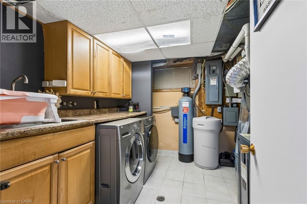 Laundry room featuring separate washer and dryer, a drop ceiling, electric panel, light tile patterned floors, and cabinet space - 3 Chicopee Terrace, Kitchener, ON - Indoor Photo Showing Laundry Room