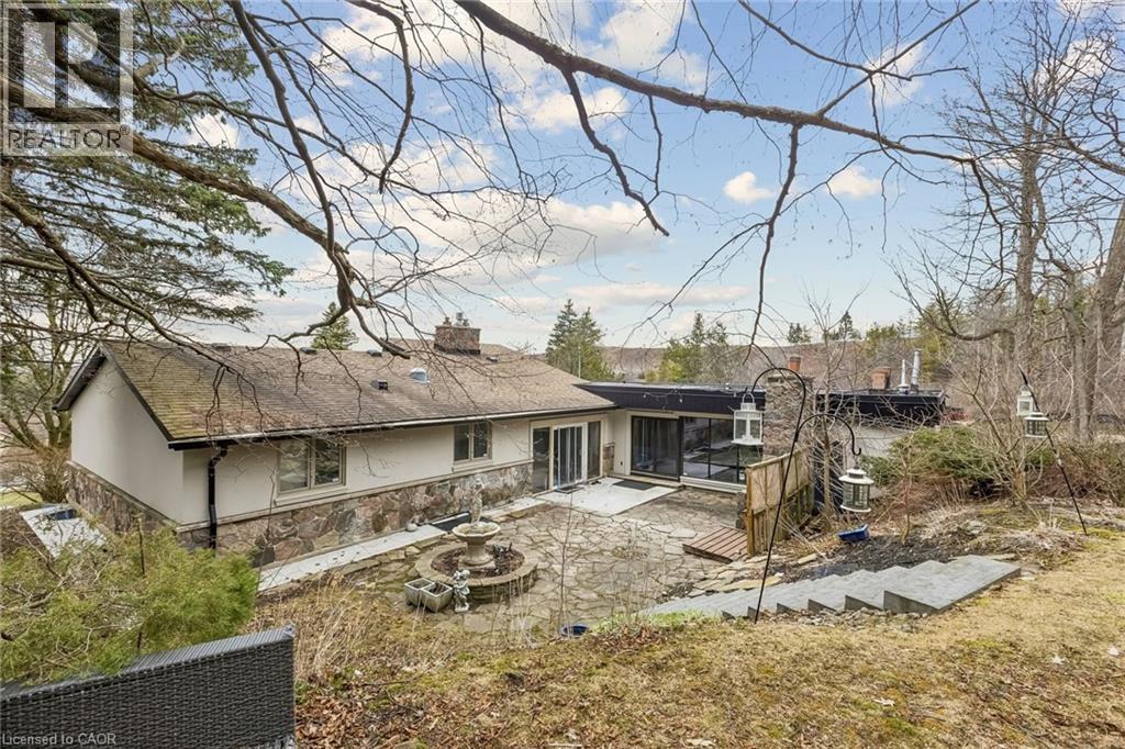 Rear view of house with a patio, a chimney, stucco siding, a sunroom, and stone siding - 3 Chicopee Terrace, Kitchener, ON - Outdoor