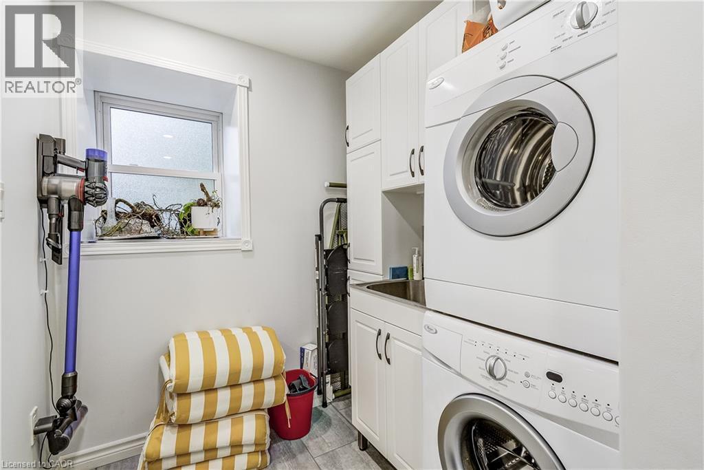 Laundry room featuring stacked washer and clothes dryer, cabinet space, and light wood-style flooring - 315 Aberdeen Avenue, Hamilton, ON - Indoor Photo Showing Laundry Room