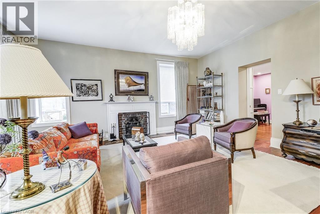 Living area featuring a fireplace with flush hearth, wood finished floors, and hanging lights - 315 Aberdeen Avenue, Hamilton, ON - Indoor Photo Showing Living Room With Fireplace