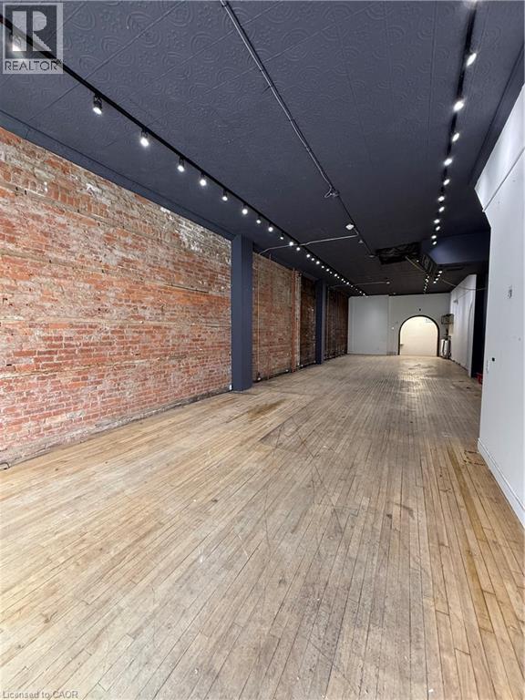 Retail Space featuring rail lighting and brick wall - 228 James Street N, Hamilton, ON