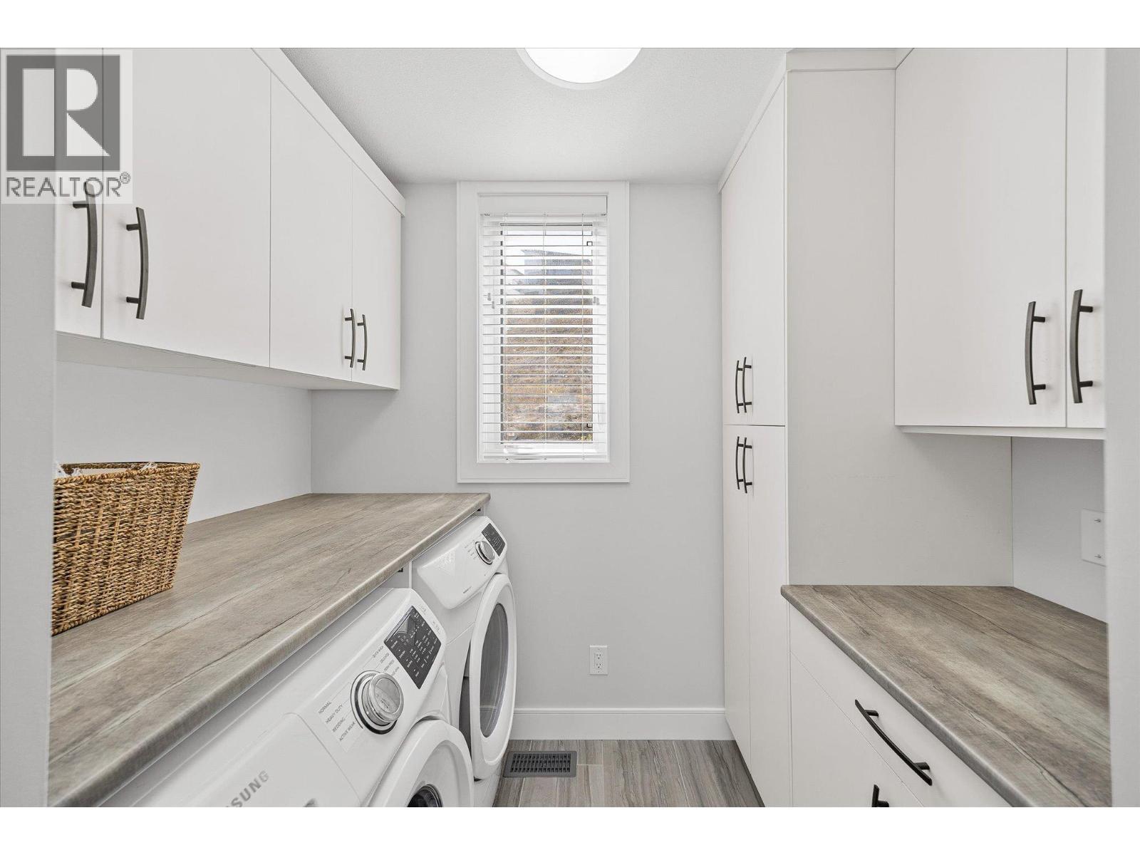 Laundry room off of the kitchen with storage and counter space - 1860 Blue Bunch Court, Kelowna, BC - Indoor Photo Showing Laundry Room