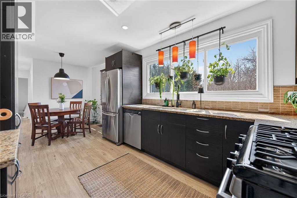 Kitchen featuring light wood finished floors, light stone counters, tasteful backsplash, modern cabinets, and dark cabinetry - 844 Upper Wellington Street, Hamilton, ON - Indoor Photo Showing Kitchen