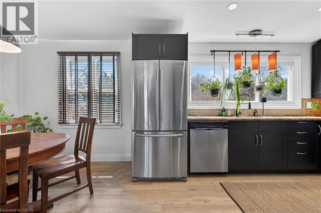 Kitchen with stainless steel appliances, light stone counters, light wood-type flooring, modern cabinets, and backsplash - 844 Upper Wellington Street, Hamilton, ON - Indoor Photo Showing Kitchen