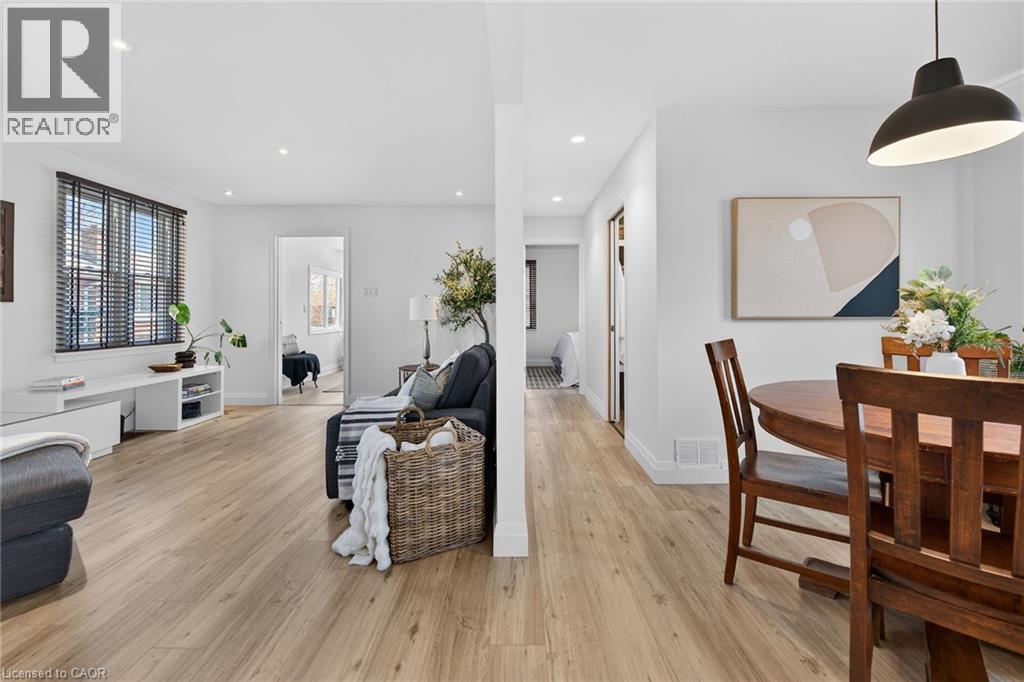 Kitchen with dark cabinetry, hanging light fixtures, stainless steel appliances, light wood-style flooring, and light stone countertops - 844 Upper Wellington Street, Hamilton, ON - Indoor
