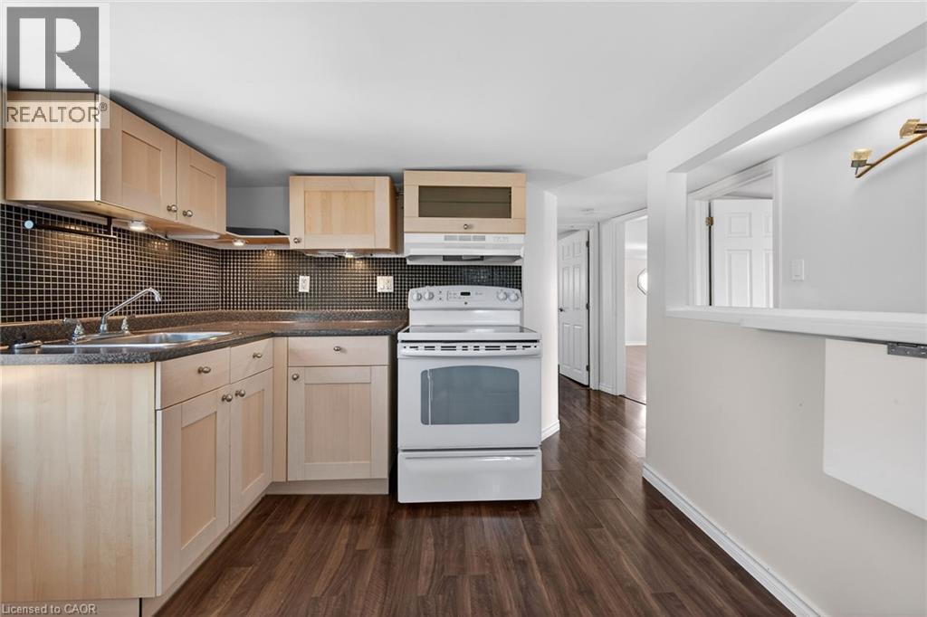 Kitchen with white range with electric stovetop, dark countertops, dark wood-type flooring, tasteful backsplash, and light wood finish cabinets - 844 Upper Wellington Street, Hamilton, ON - Indoor Photo Showing Kitchen