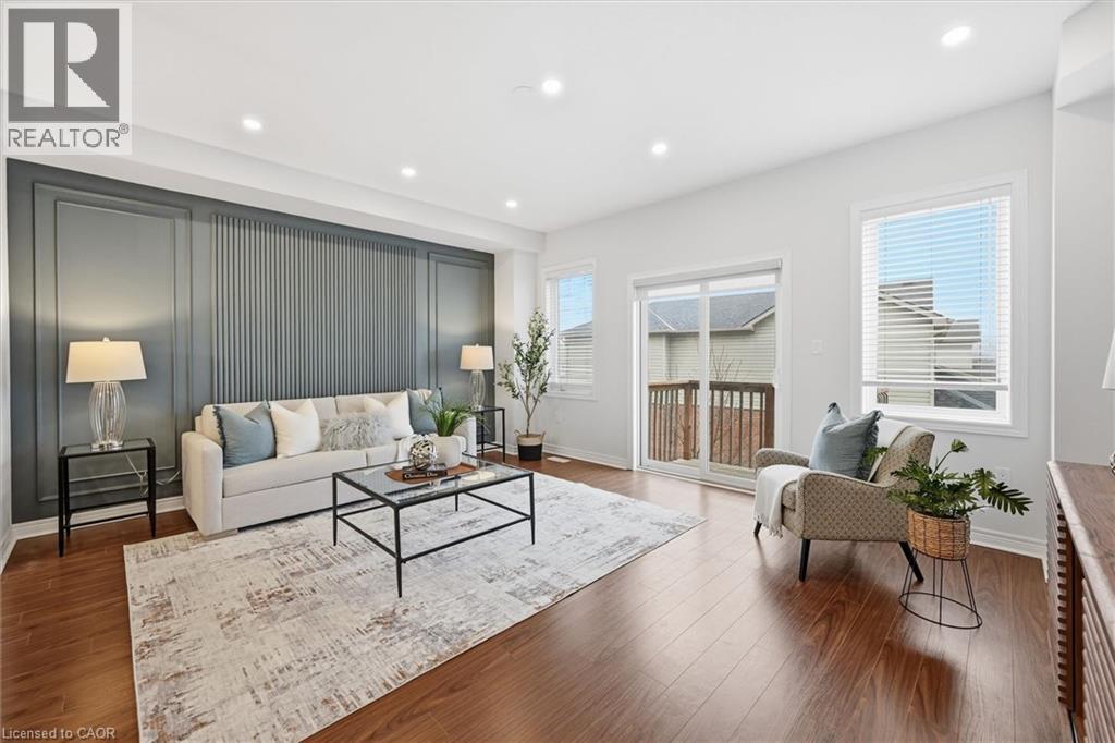 Living room with feature accent wall, abundant natural light, pot lighting and wood finished floors - 122 E Dundas Street E Unit# 9, Waterdown, ON - Indoor Photo Showing Living Room