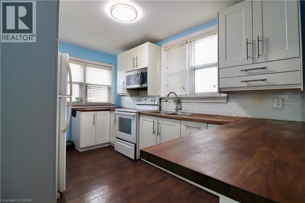 Kitchen with butcher block counters, white appliances, white cabinetry, decorative backsplash, and dark wood finished floors - 80 Roseview Avenue, Cambridge, ON - Indoor Photo Showing Kitchen With Double Sink