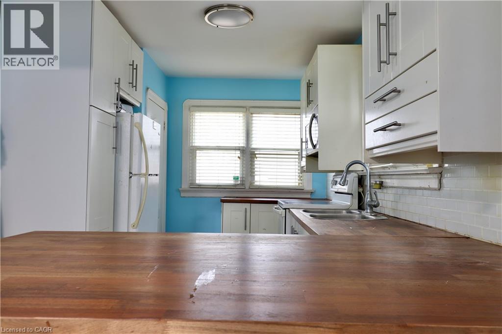 Kitchen with wooden counters, white cabinets, freestanding refrigerator, range with electric stovetop, and stainless steel microwave - 80 Roseview Avenue, Cambridge, ON - Indoor Photo Showing Kitchen With Double Sink