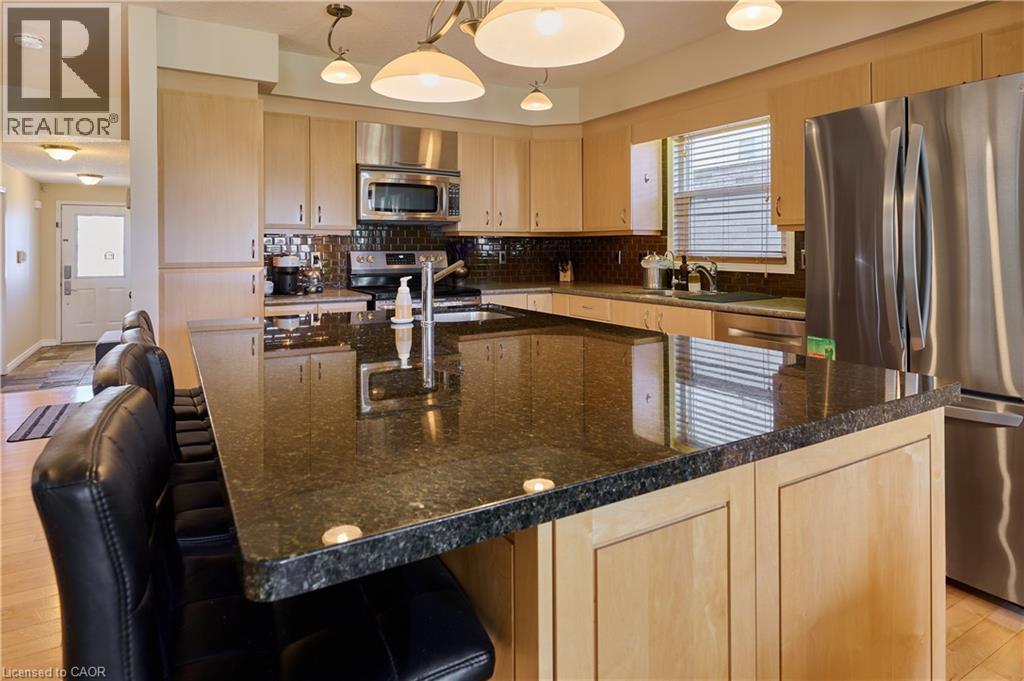 Kitchen featuring light wood finish cabinets, stainless steel appliances, a kitchen island with sink, and dark stone countertops - 126 Snowdrop Crescent, Kitchener, ON - Indoor Photo Showing Kitchen With Stainless Steel Kitchen