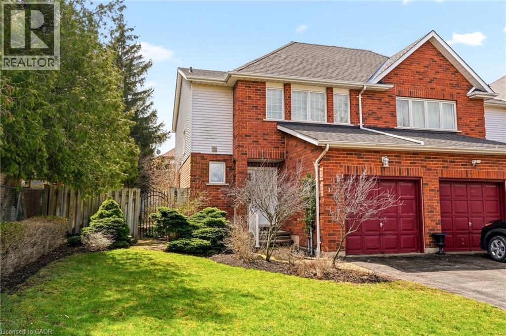 The property features a brick exterior, a driveway, and a front yard with a lawn and mature trees - 1 Tomahawk Drive, Grimsby, ON - Outdoor