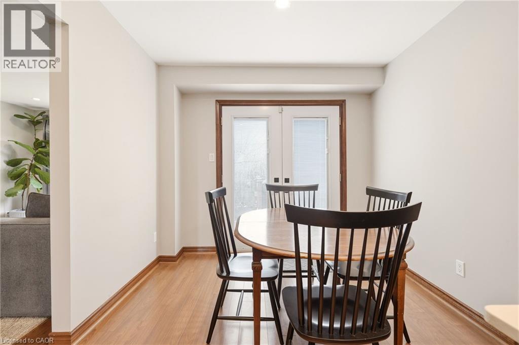 This room features light-colored walls, wood flooring, and a set of white french doors with blinds - 1 Tomahawk Drive, Grimsby, ON - Indoor Photo Showing Dining Room