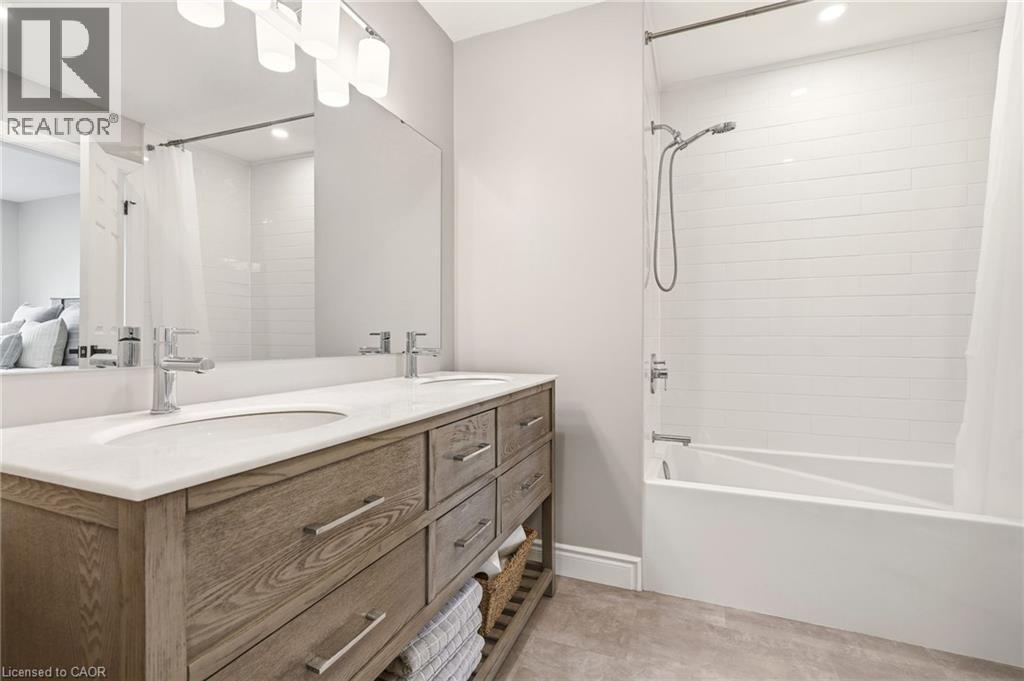 Bathroom featuring a double vanity with a light wood finish, white countertops, two sinks, and a large mirror - 1 Tomahawk Drive, Grimsby, ON - Indoor Photo Showing Bathroom