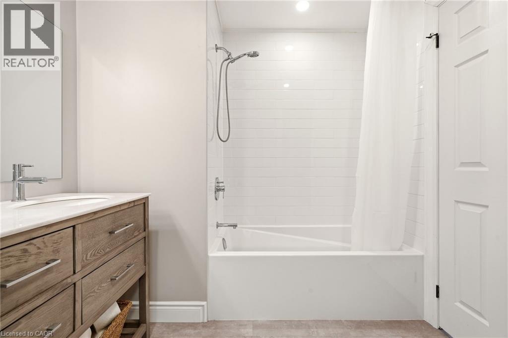 The bathroom features a vanity with a white countertop and a rectangular sink, accompanied by a wall-mounted mirror - 1 Tomahawk Drive, Grimsby, ON - Indoor Photo Showing Bathroom